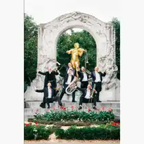 Sechs Musiker mit Blechblasinstrumenten posieren vor einem kunstvollen wei&szlig;en Pavillon mit goldener Statue in einer Parkanlage. Die Gruppe ist auf mehreren Stufen arrangiert, umgeben von Blumenbeeten und Gr&uuml;nfl&auml;chen