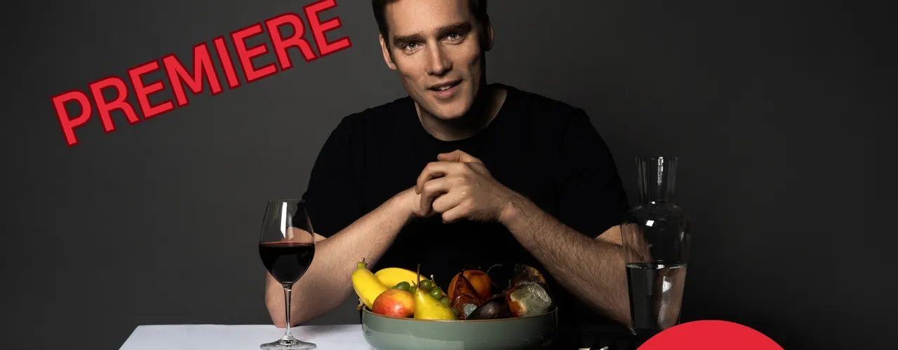 Plakatmotiv mit dunklem Hintergrund: Eine Person sitzt an einem Tisch mit Obstschale, Weinglas und Karaffe. Dar&uuml;ber steht der Text &bdquo;Paul Sommersguter &ndash; Halbzeit&ldquo;. Schr&auml;g links ist das Wort &bdquo;Premiere&ldquo; in Rot platziert. Rechts befindet sich ein roter Kreis mit der Aufschrift &bdquo;Magic &amp; Comedy&ldquo;. Unten steht &bdquo;Staunen f&uuml;r Fortgeschrittene&ldquo; sowie die Website &bdquo;www.paul.live&ldquo;.